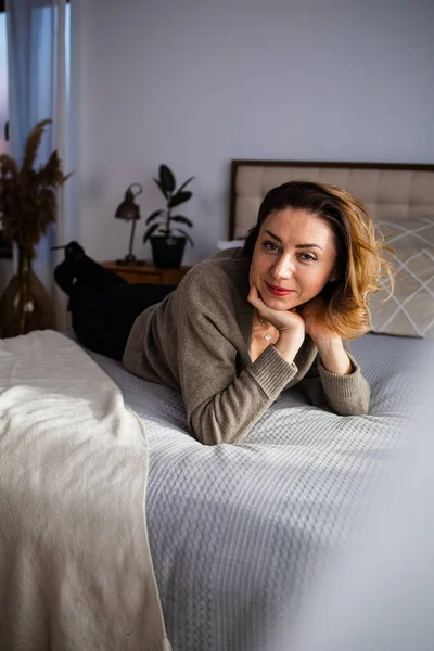 Başarılı orta yaşlı kadın evde gülümsüyor. Kızıl saçlı, orta yaşlı, güzel bir kadın.