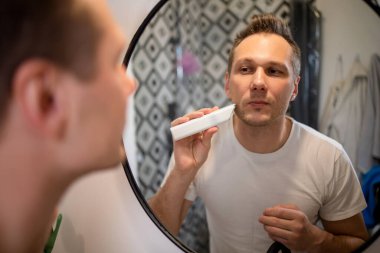 Sakalını budayarak sakalını kesen yakışıklı genç bir adam.