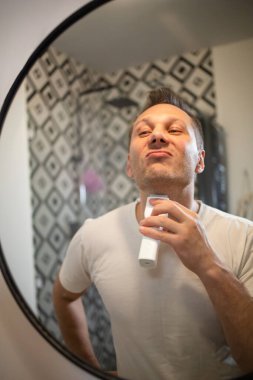 Sakalını budayarak sakalını kesen yakışıklı genç bir adam.