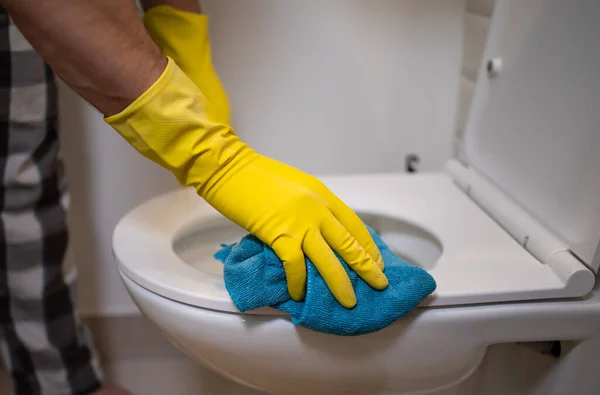 戴着手套的男人在浴室里用海绵擦拭马桶 — 图库照片