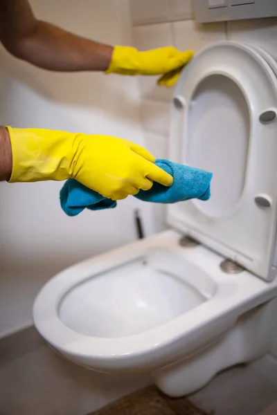 戴着手套的男人在浴室里用海绵擦拭马桶 — 图库照片