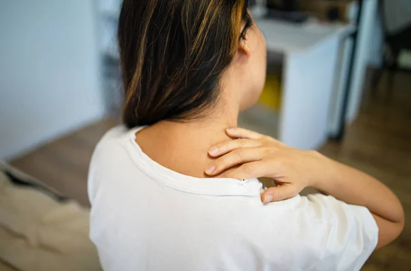 Shoulder pain. Forearm pain, people with body muscle problems, healthcare and medicine concept. Attractive woman is sitting on the bed and holding her sore shoulder with her other hand.