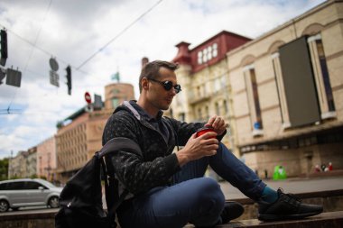 Yakışıklı bir delikanlının şehirde kahve içerken çekilmiş fotoğrafı..