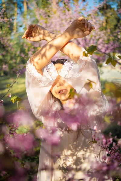 Parkta çiçek açan kiraz çiçekleriyle güzel, genç Asyalı kadın.