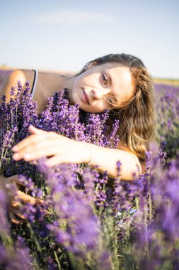 Güneşli bir günde lavanta tarlasında oturmuş temiz hava soluyan rahat, güzel bir kadın.