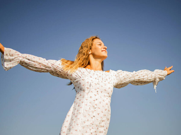 Young Happy Beautiful Blonde Woman Cheering Open Arms with Blue sky background.