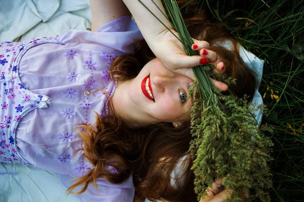 美丽的小女孩 长长的红色卷曲的头发 一波波的头发躺在绿草上 从上往下看 — 图库照片