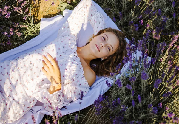 年轻美丽的金发女子躺在薰衣草地里 — 图库照片