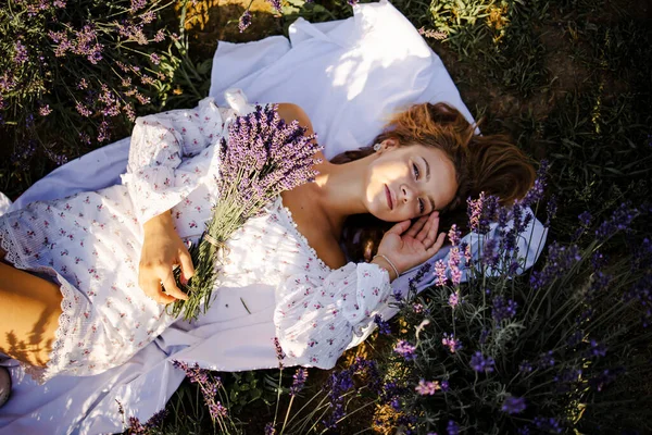 年轻美丽的金发女子躺在薰衣草地里 — 图库照片
