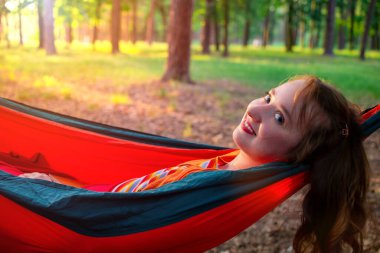 Genç ve güzel bir kadın yeşil bir ormanda rahat bir hamakta dinleniyor..