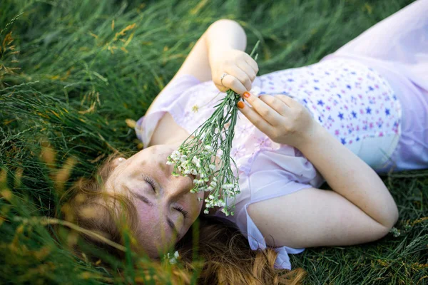 一个红头发的漂亮的年轻性感女子的红头发画像 躺在春日的阳光下 躺在青草上悠闲自在 — 图库照片
