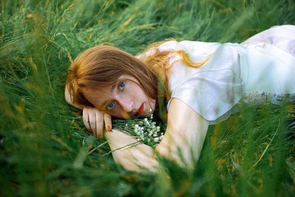 一个红头发的漂亮的年轻性感女子的红头发画像 躺在春日的阳光下 躺在青草上悠闲自在 — 图库照片