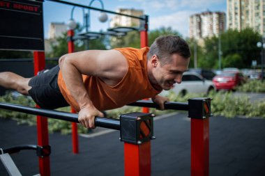 Güçlü sporcu şehir dışında antrenman yapıyor. Çapraz antrenman sırasında şınav çeken genç bir adam..