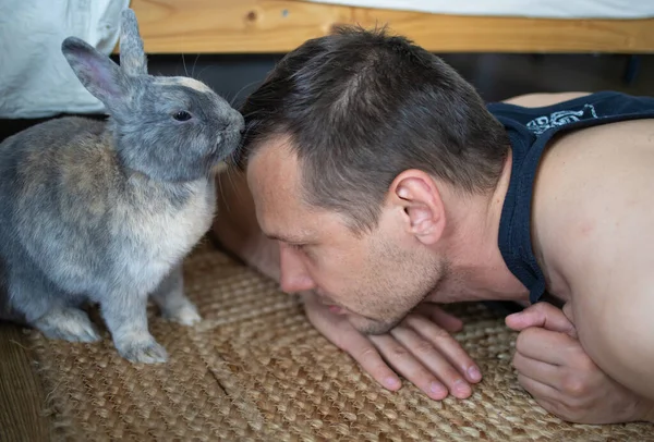 A pet rabbit is licking a man\'s head