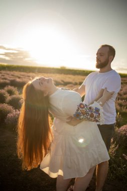 Genç bir çift gün batımında lavanta tarlasında birbirlerine sarılıyorlar.