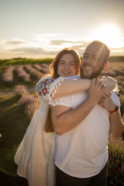 A young couple in love hugging in the lavender field at sunset