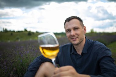 Genç adam gün batımında Fransa 'da lavanta tarlasında şarap içiyor.