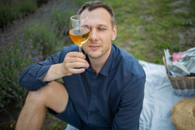 Genç adam gün batımında Fransa 'da lavanta tarlasında şarap içiyor.