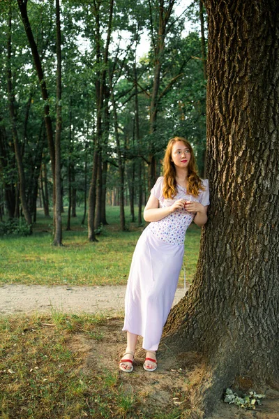 红发女孩在深树林中摆姿势靠近树 — 图库照片