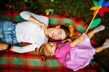 Happy harmonious family outdoors. Young mother and daughter spend joint activities on holidays.