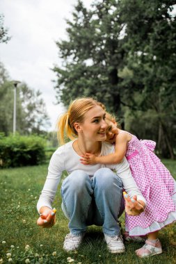 Happy young mother with her little daughter in summer park