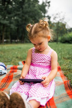 Little girl playing with a smartphone watching a cartoon in the Park