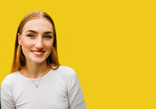 portrait of a beautiful positive red-haired girl with arrows on the eyes isolated on yellow background.