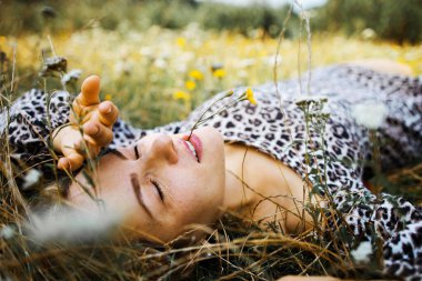 Summer lifestyle portrait middle aged woman lying on the grass outdoor. spends time in nature in summer.