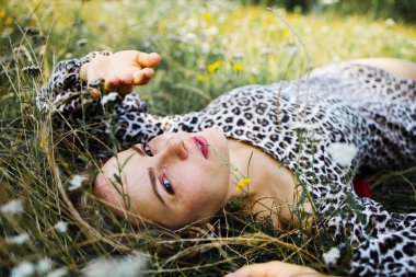Summer lifestyle portrait middle aged woman lying on the grass outdoor. spends time in nature in summer.