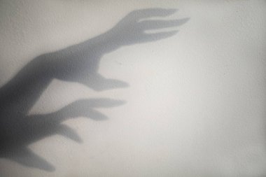 big monster claw shadow on wall. Horror hand shadow on a white background, copy space.