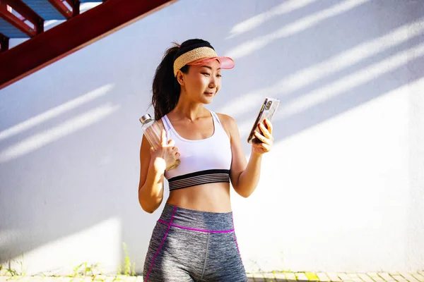 Fitness Concept Happy Asian Woman Holding Water Bottle Using Smartphone — Stockfoto