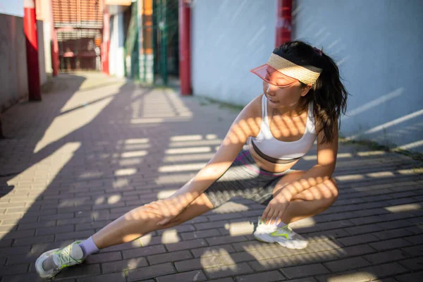 Fitness sport asian girl in fashion sportswear doing yoga fitness exercises on the street, outdoor sports, urban style