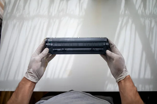 hands repairing laser toner cartridge. Refilling toner in a laser printer cartridge, office equipment maintenance concept.