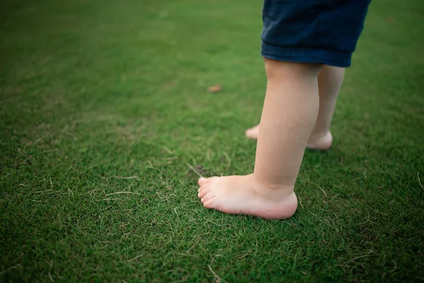 Boy feet in nature. bare feet in the green grass. little Happy child running at sunset barefoot outdoor. Concept of happy childhood