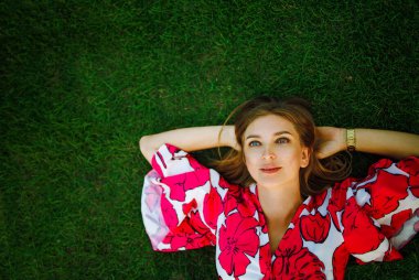 Beautiful young blonde woman lies on the grass. Fresh natural summer concept. View from the top with copy space.