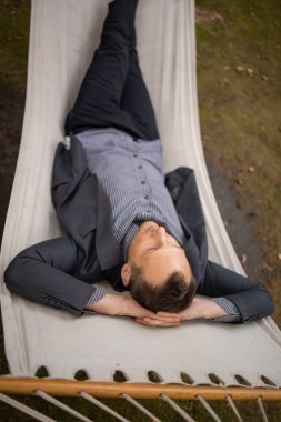 Yorgun işadamı parkta hamakta dinleniyor..