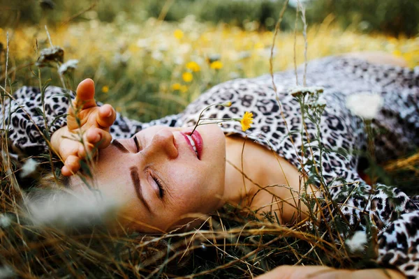 中年妇女躺在野外野花地里 面带微笑 — 图库照片