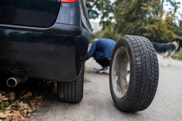 A man changes a wheel after a car breaks down. Transport, travel concept