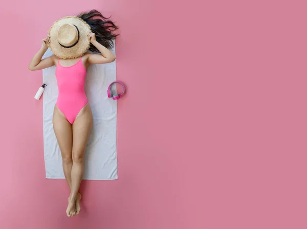 身穿粉色泳衣耳机的年轻女子的头像是用黄色背景的毛巾听音乐 海上休息 晒黑的概念 — 图库照片