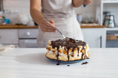 Ev hanımı doğum günü çikolatalı pasta tatlısı için son rötuşları yapıyor. Bir kadın, çikolatalı ve fındıklı kolay bir tarifle ev yapımı kek yapar..