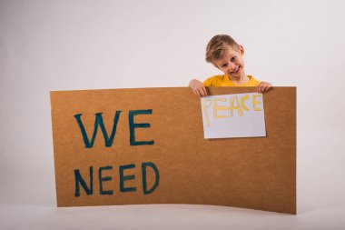 Barışa ihtiyacımız var. İhtiyacımız olan kelimelerle dolu tahtayı tutan küçük mutlu çocuk