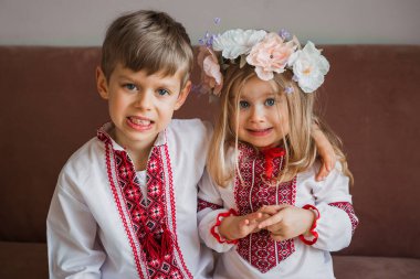 Slav ulusal kıyafetleri içinde küçük bir kız ve oğlan kanepede. Ukrayna