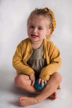 2 yaşında, gülümseyen bir kız çocuğu beyaz bir arka planda. 