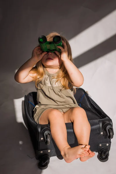 Chica Mirando Prismáticos Sintiéndose Infeliz Sentada Maleta — Foto de Stock