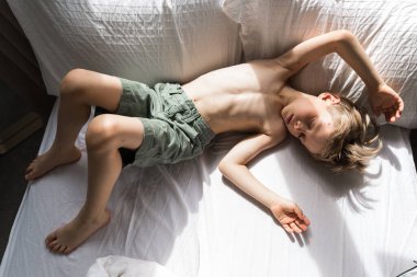 Bebek elinde oyuncak, suçiçeği olan çocuk, yatakta yatıyor.