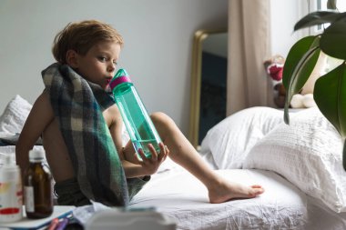 Su içen suçiçeği olan küçük bir çocuk. 