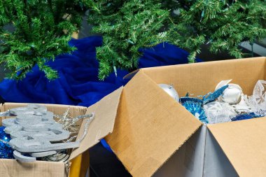 Yeni yıldan sonra Noel süslerini paketliyorum. Boş ağaç ve eteğin önünde dolu kutular.
