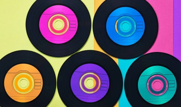Colorful vinyl CD discs in flat lay format displayed on a multicolored background, retro records conceptual image.