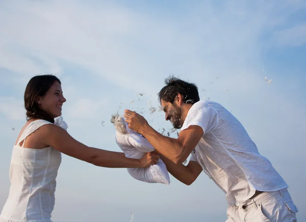 Young couple fighting pillows on the beach — Stock Photo, Image