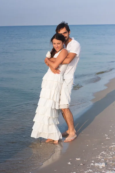 Молодая пара в белой одежде на пляже — стоковое фото